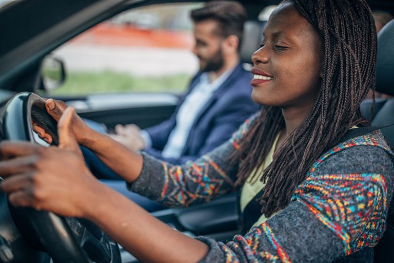smiling woman driver with male passenger in front seat
