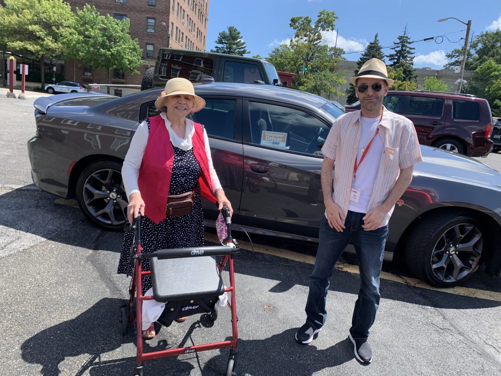 volunteer driver standing next to rider who is using a rolling walker