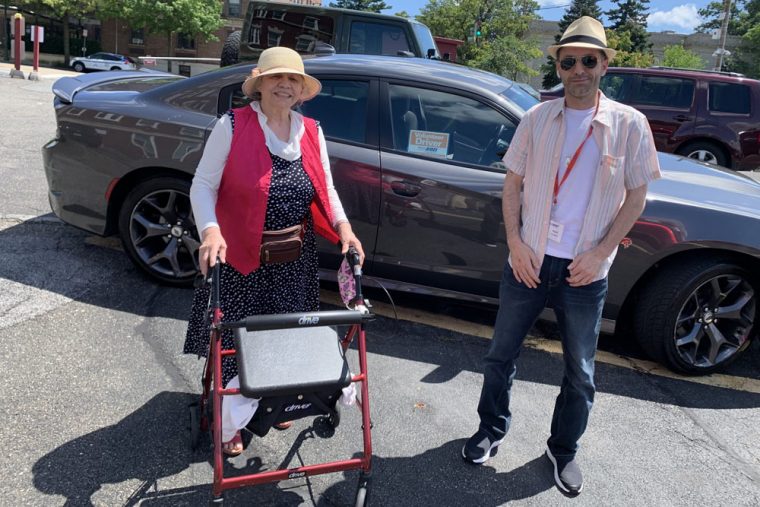 volunteer driver standing with driver in front of his car