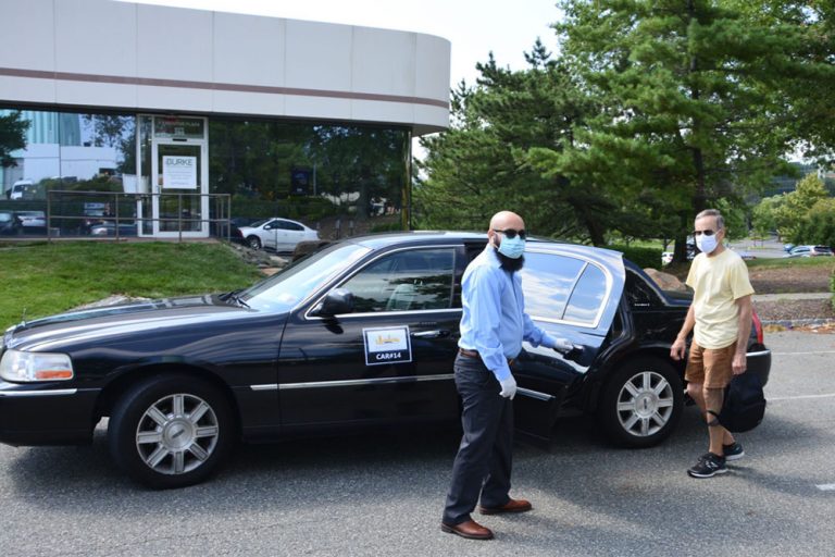 masked man opening door for masked rider into black car