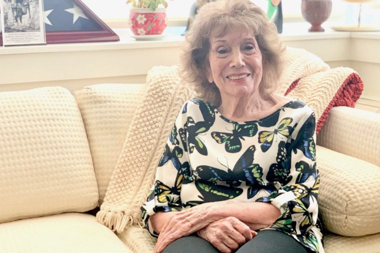 older woman sitting on off white color couch