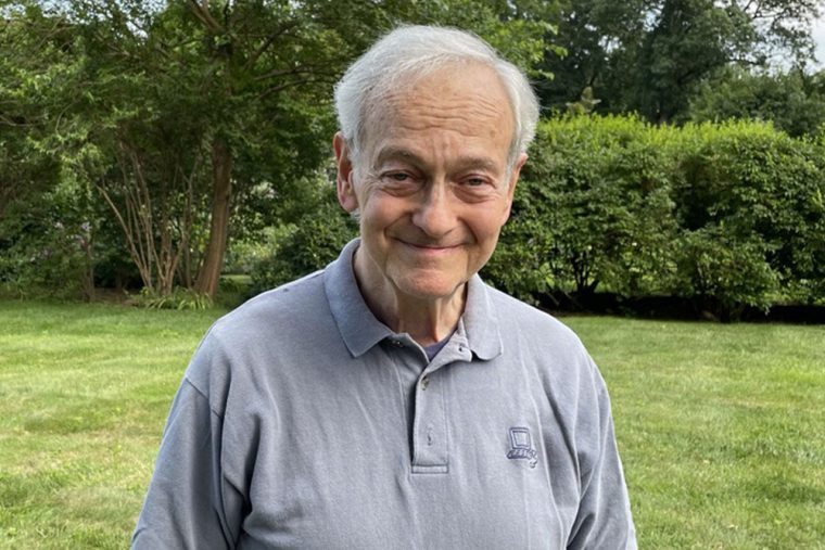 head shot of man with a smile against green lawn and bushes