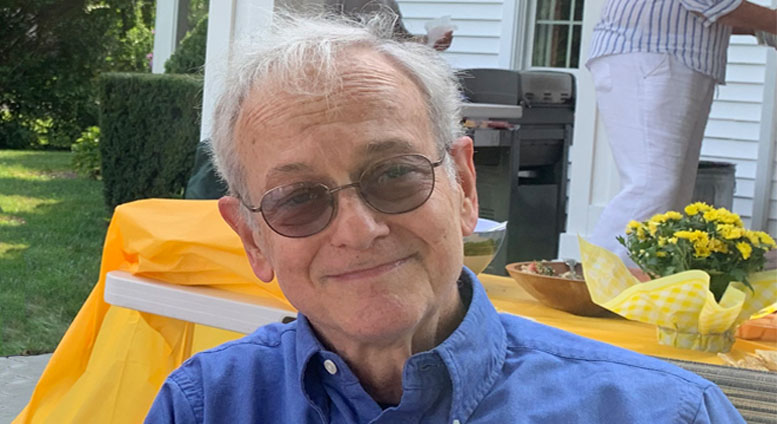 older man in blue shirt wearing sunglasses sitting