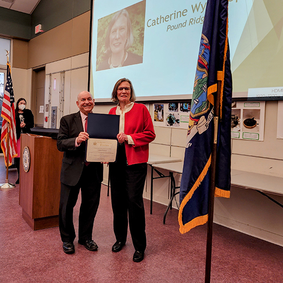 Woman in red sweater receiving citation from man in suit 