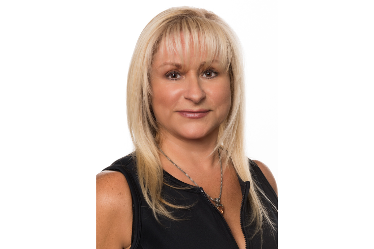 head shot of woman volunteer driver with blond hair and black blouse looking directly at camera