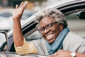 Smiling driver with curly grey hair smiling and waving out window