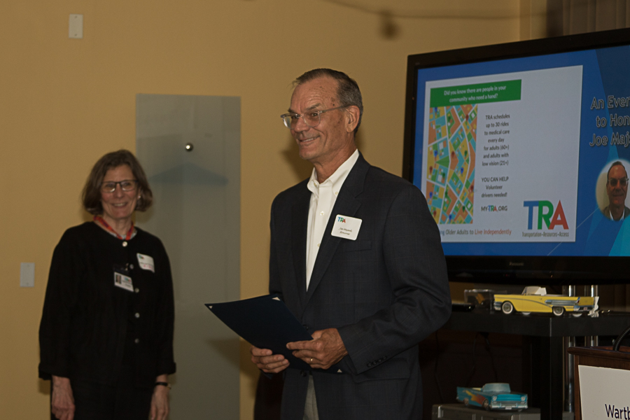 Joe Majsak standing in front of media presentation of TRA work