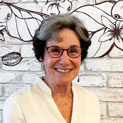 smiling woman wearing glasses and white blouse