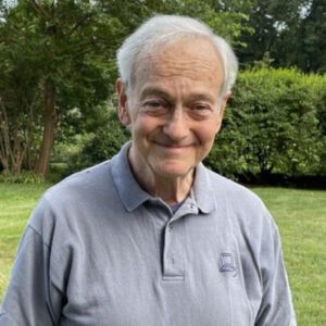 smiling older man against a green foliage background
