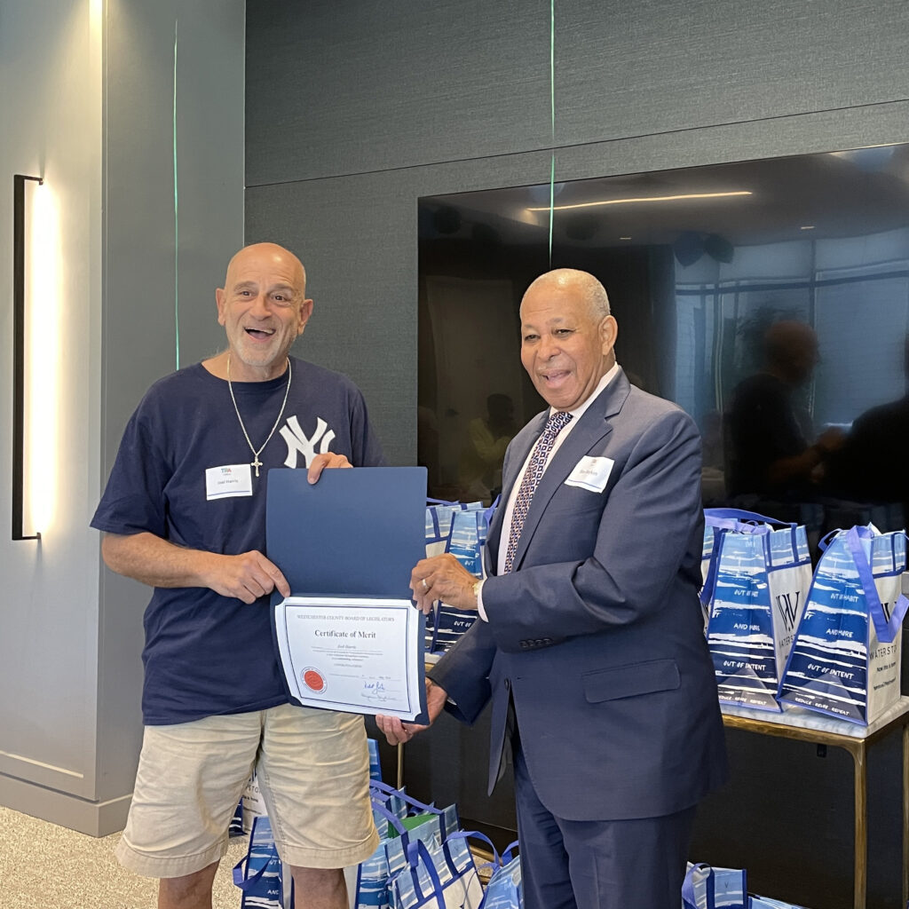 volunteer driver, smiling widely, receives certificate of merit from Legislator Boykin
