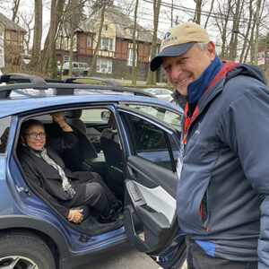 Man holds door open for woman as she gets in back seat of car