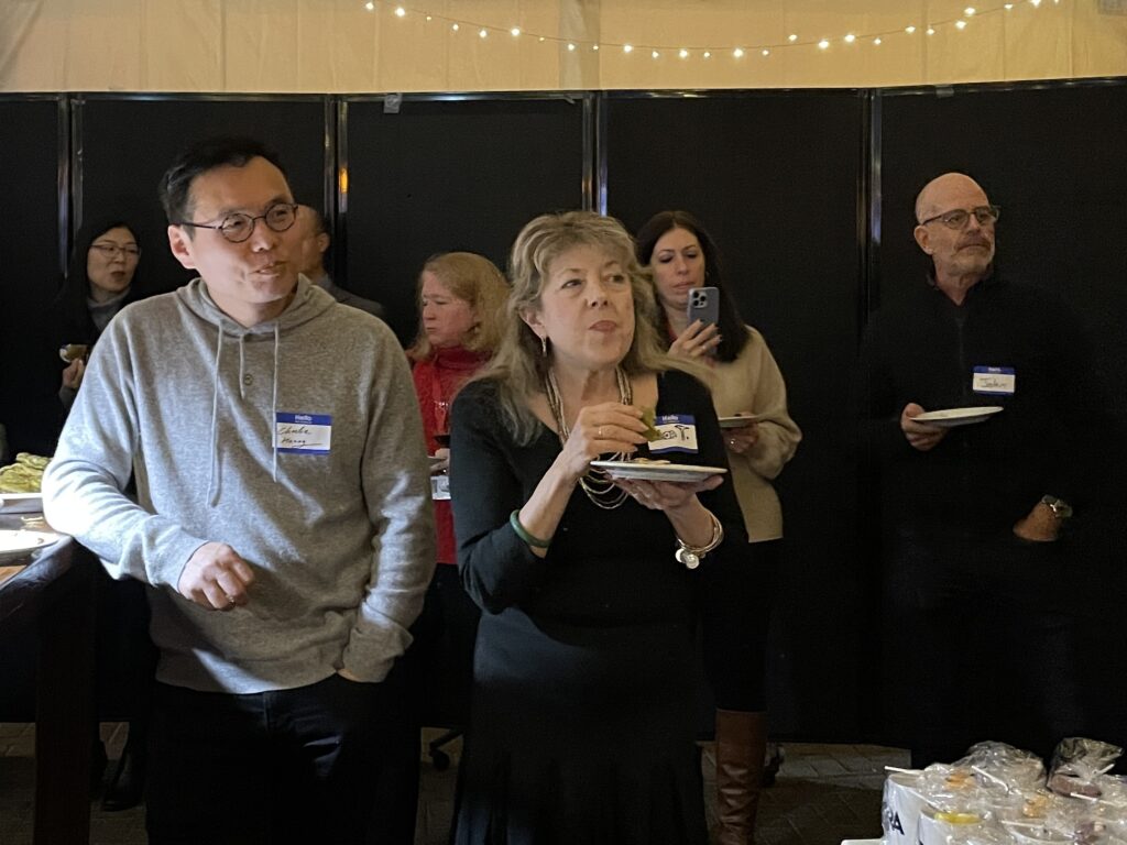 People stand and eat while listening to what someone off camera is saying