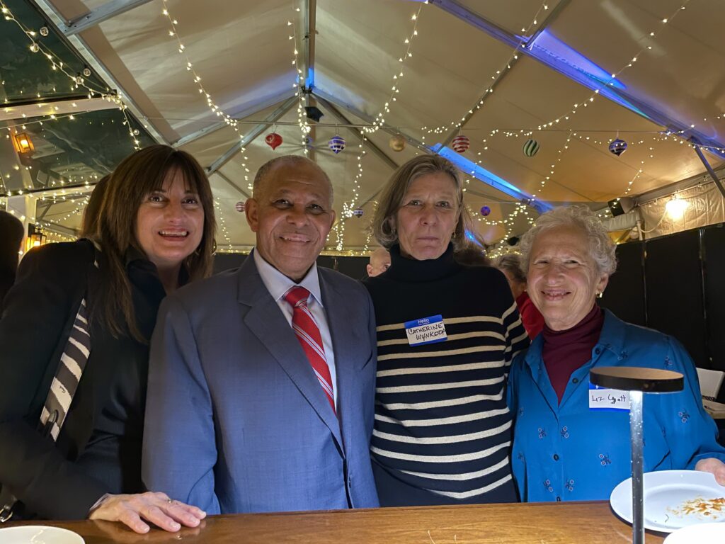 Four adults three woman and one man stand by high top table