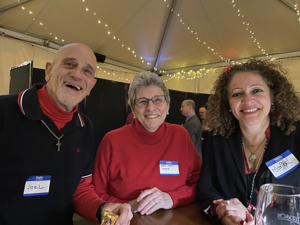 Smiling man stands with two smiling women