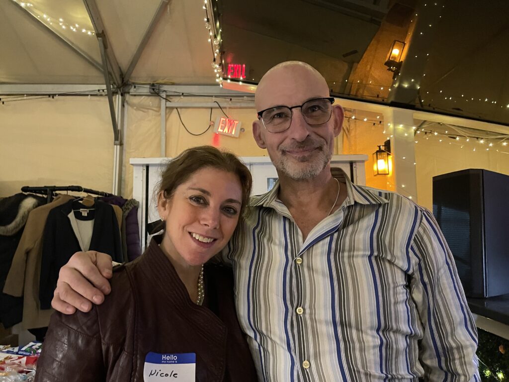 Smiling woman leans her head toward a taller man with hand on her shoulder