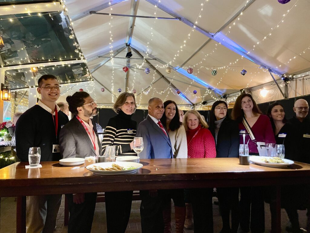 Ten adults posing standing behind a high top table