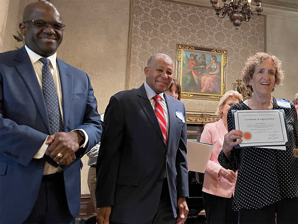 County exec and county legislator stand next to woman holding volunteer certificate