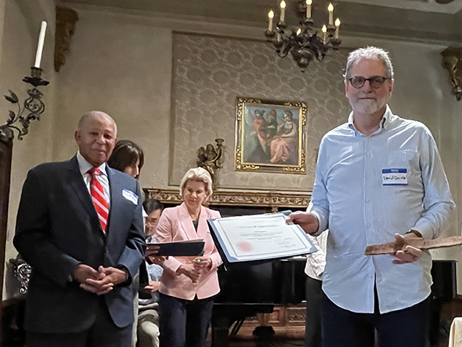 volunteer driver in blue button down shirt holds his volunteer certificate