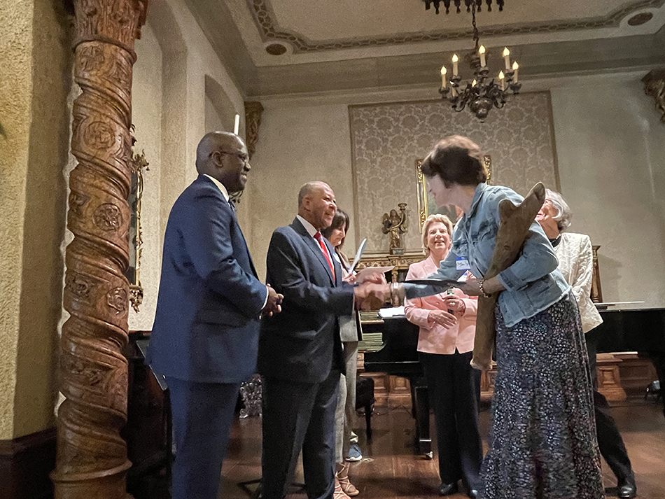 Woman holding volunteer award extends hand to county legislator