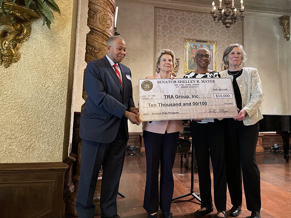 Four people standing holding oversize check