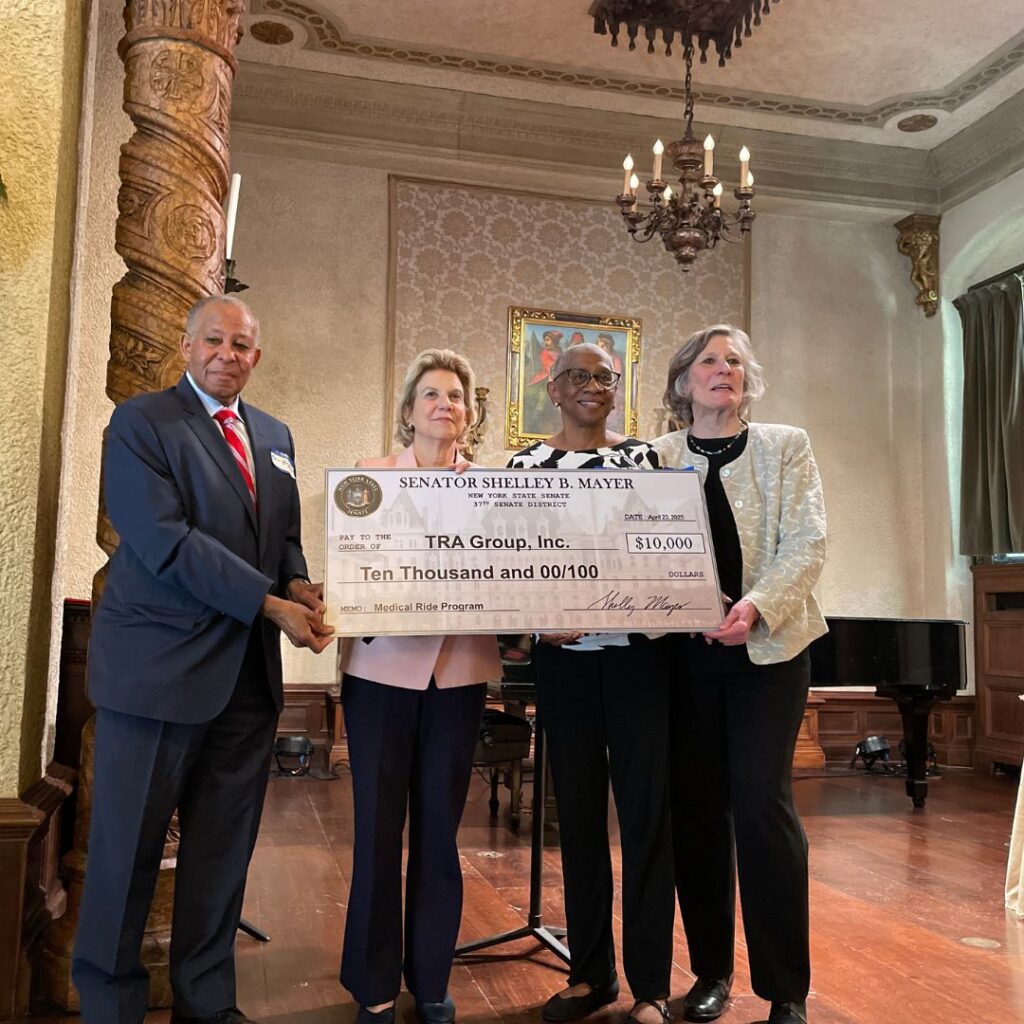 Three women and one man holding oversize image of a check
