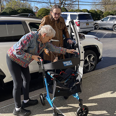 woman assists a second woman to access her walker