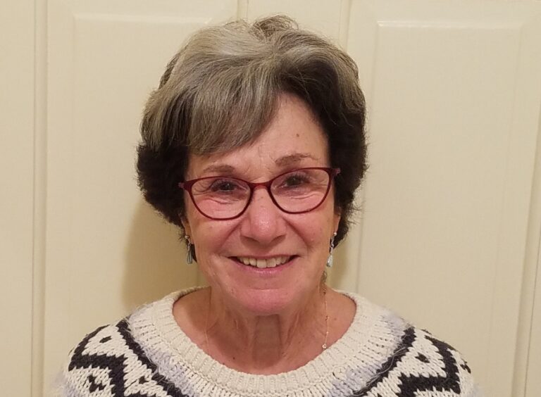 headshot of smiling woman with grey hair and Red eyeglasses