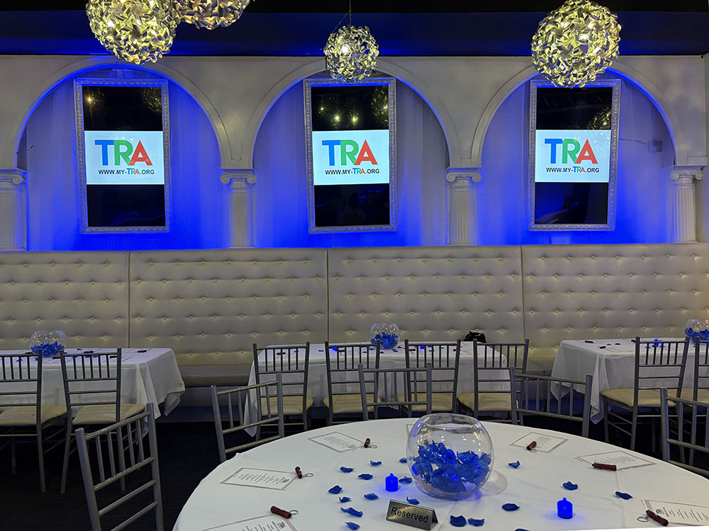 horizontal photo of dining room in restaurant showing tables with white tablecloths and blue decorations
