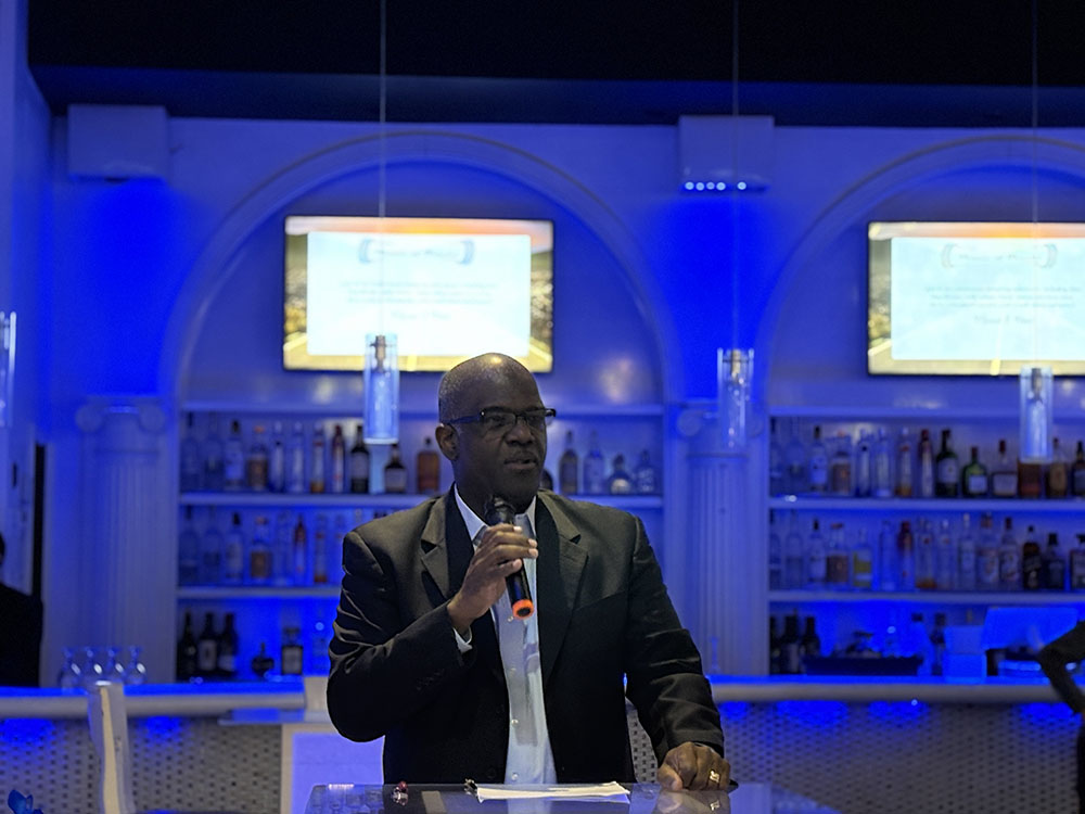 Man in dark colored suit speaks from the podium