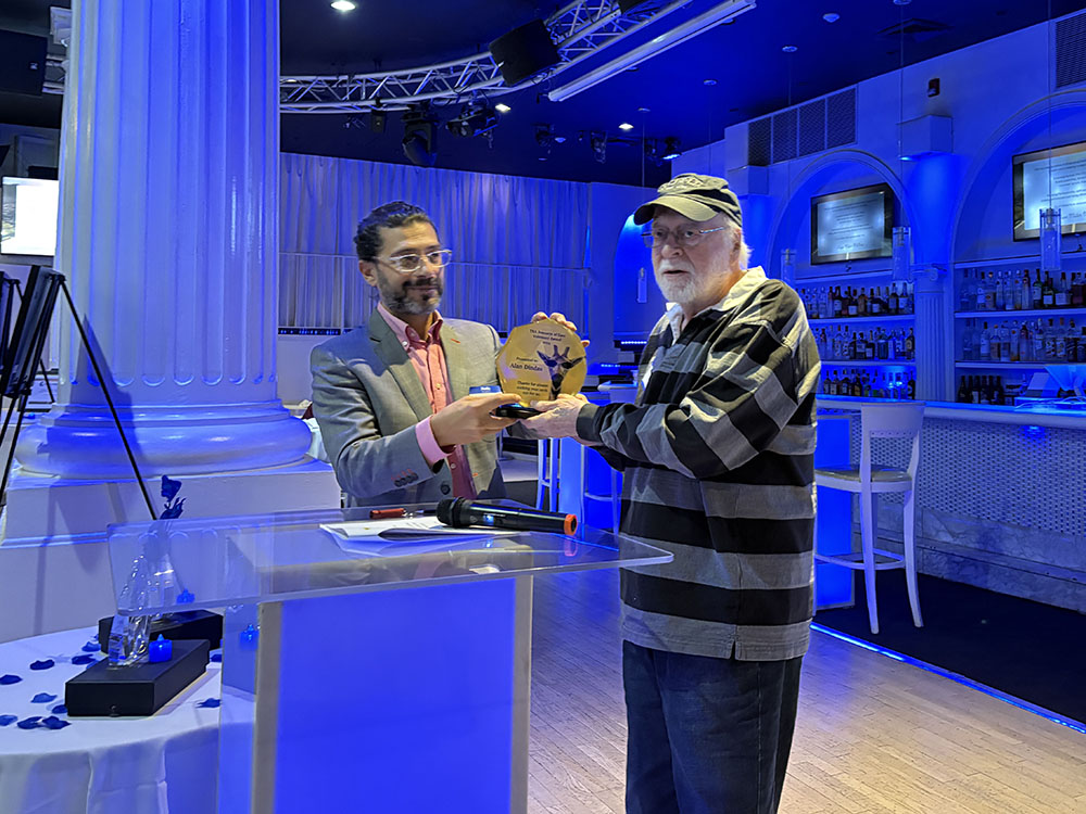 standing at the podium the emcee hands the awarded his award