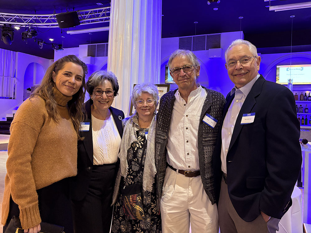 Group of five people stand in restaurant dining room for photo
